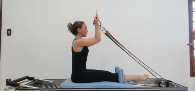 photo of woman sitting on a pilates reformer machine