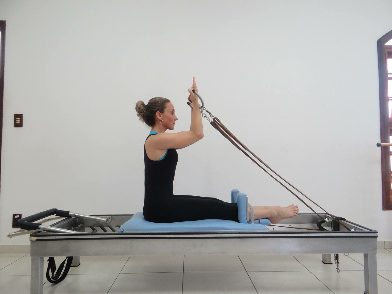 photo of woman sitting on a pilates reformer machine