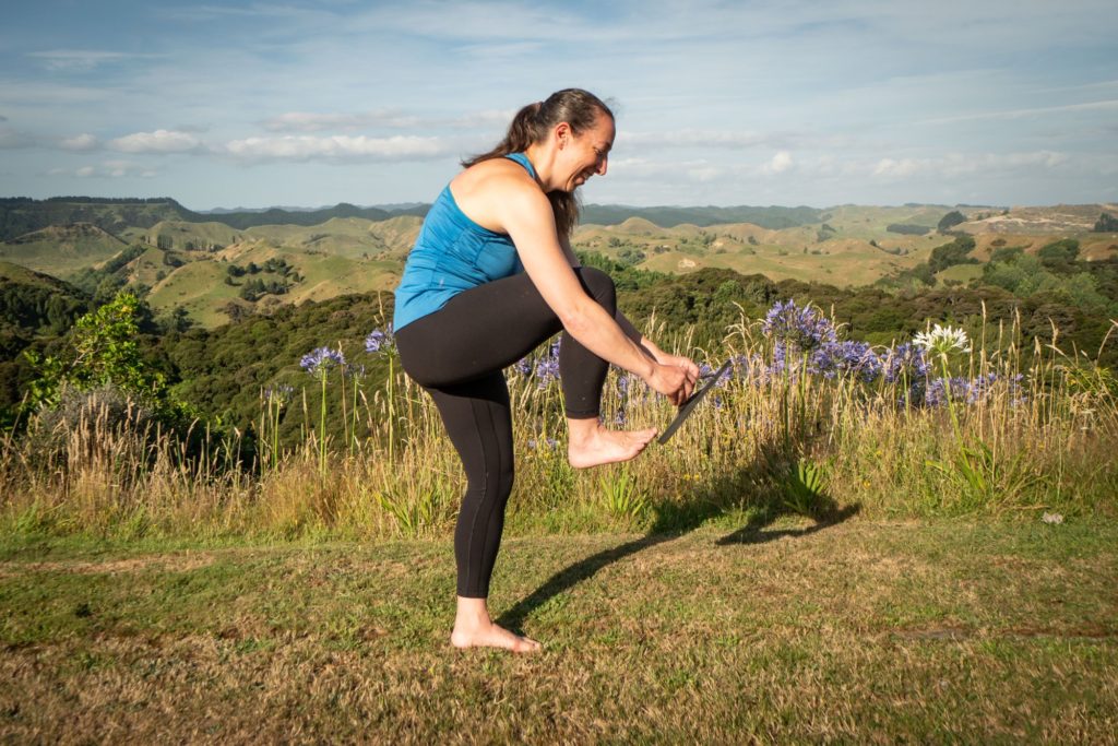 standing on one leg lifting up the other leg to put on shoe