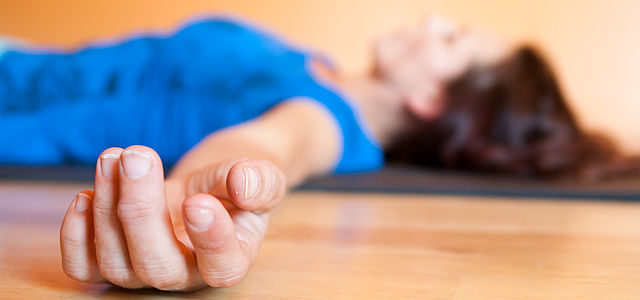 photo of a woman lying in savasana pose zoomed in on her outstretched hands