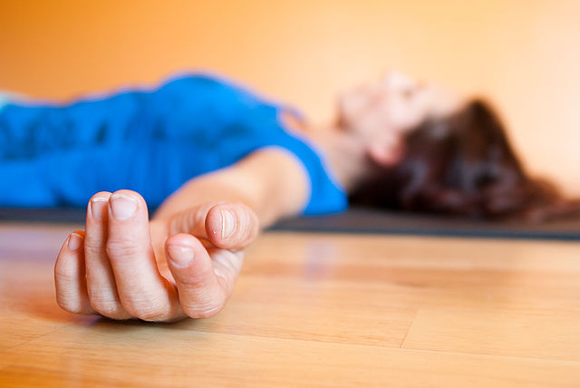 photo of a woman lying in savasana pose zoomed in on her outstretched hands