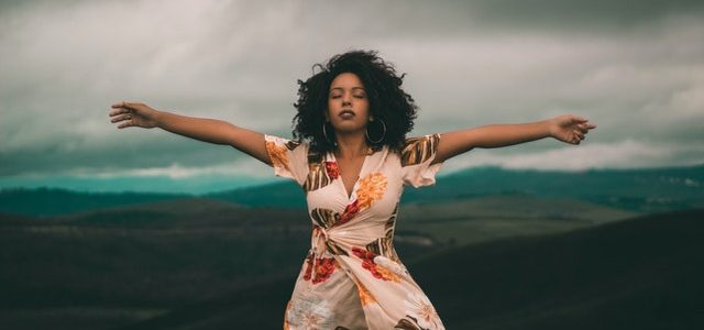 woman standing with arms open eyes closed, relaxed breathing