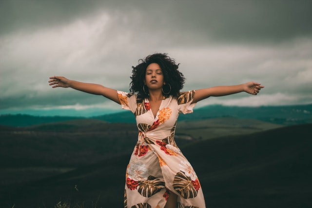 woman standing with arms open eyes closed, relaxed breathing