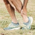 the lower part of a man's legs, grabbing his injured ankle with one hand