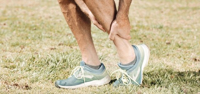 the lower part of a man's legs, grabbing his injured ankle with one hand