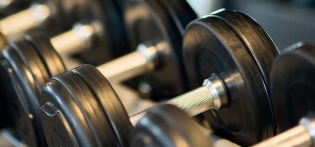 black and sliver barbells sitting on a rack