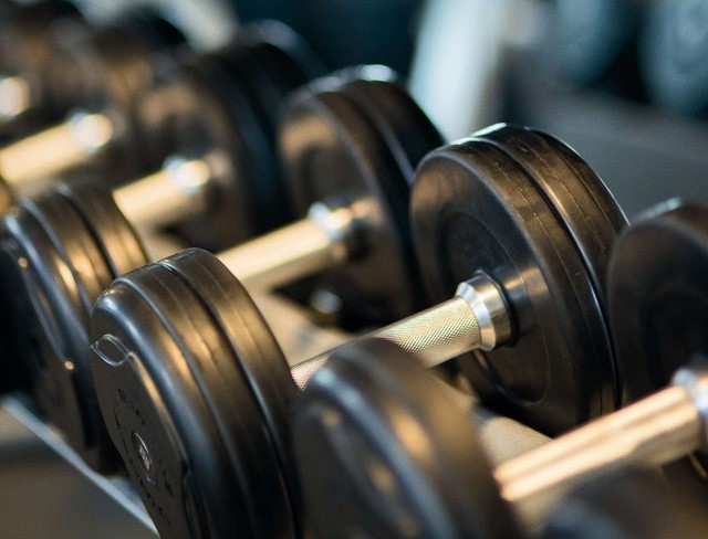 black and sliver barbells sitting on a rack