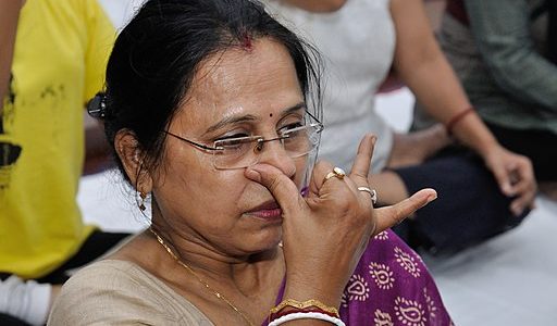 a woman with her fingers on her nose doing alternate nostril breathing