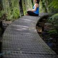 a woman sitting on a path in the forest thinking