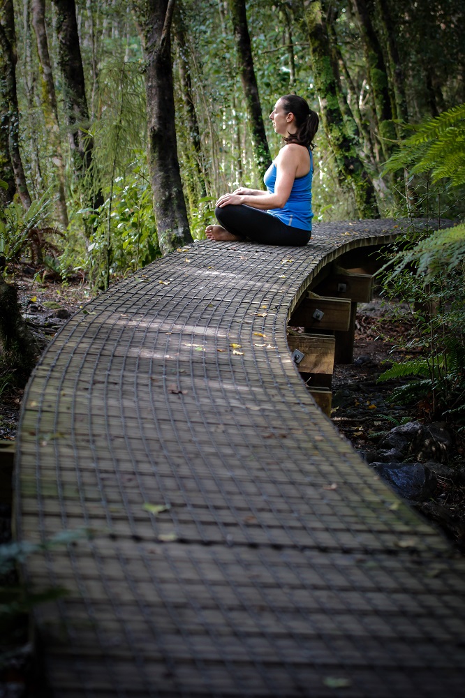 a woman sitting on a path in the forest thinking